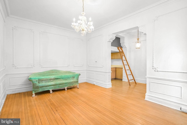 interior space with an inviting chandelier, light hardwood / wood-style flooring, and crown molding