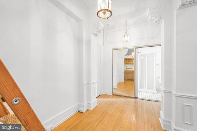 corridor with hardwood / wood-style floors and an inviting chandelier