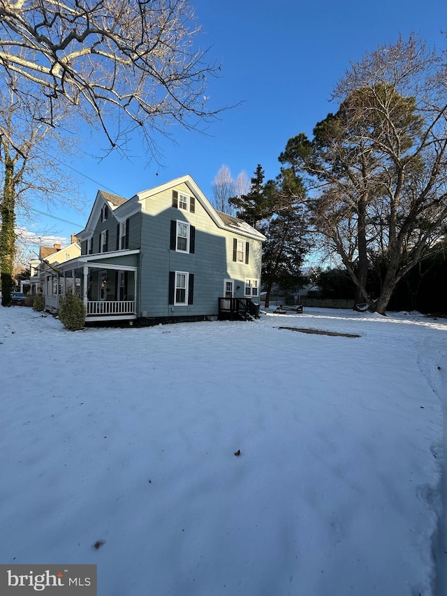 snow covered back of property with a sunroom