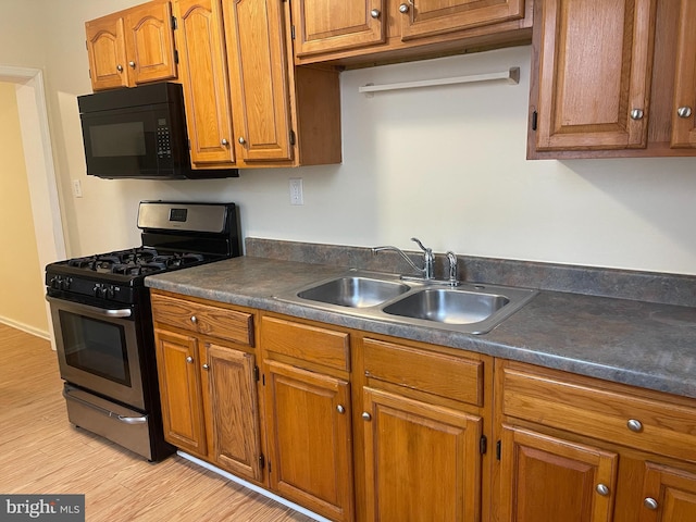 kitchen featuring stainless steel gas range, sink, and light hardwood / wood-style flooring