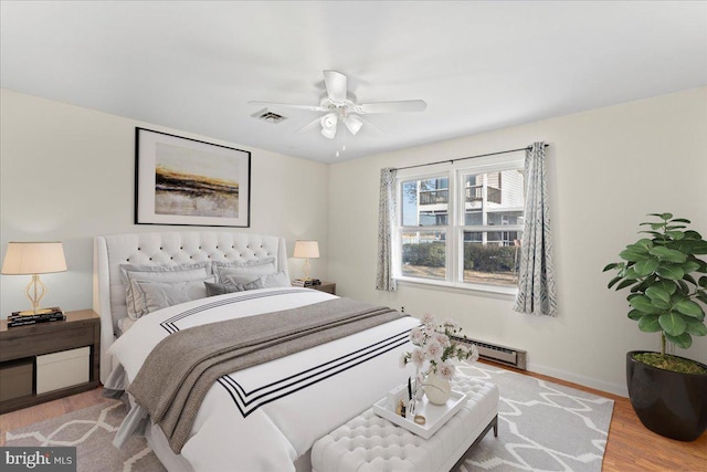 bedroom featuring hardwood / wood-style flooring, a baseboard radiator, and ceiling fan