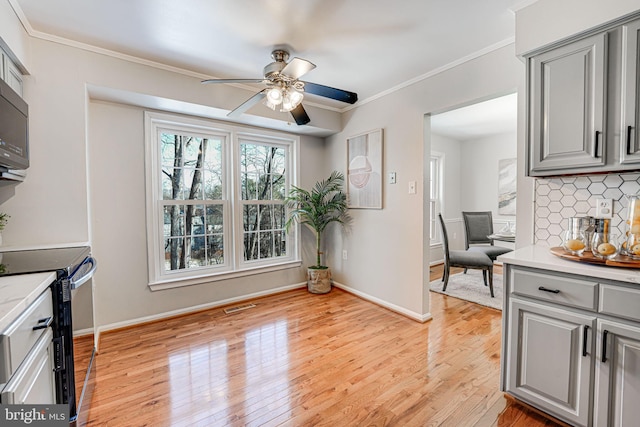 kitchen featuring gray cabinetry, tasteful backsplash, crown molding, light wood-type flooring, and electric stove