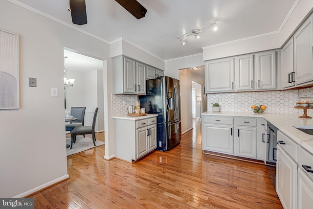 kitchen with ceiling fan with notable chandelier, tasteful backsplash, light stone counters, fridge with ice dispenser, and light hardwood / wood-style flooring