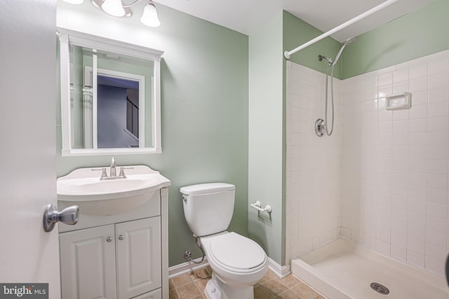 bathroom with vanity, tile patterned floors, toilet, and a tile shower