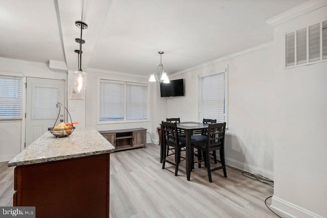 dining space featuring an inviting chandelier, ornamental molding, and light hardwood / wood-style flooring