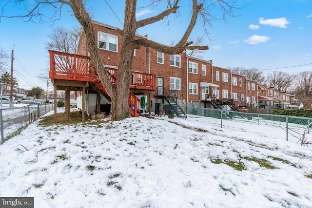 snow covered back of property featuring a deck