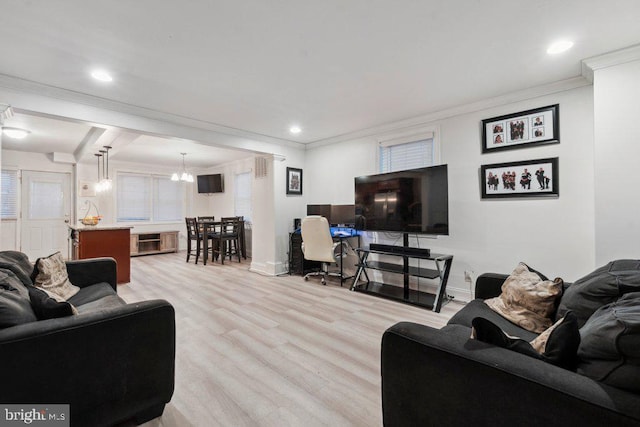 living room with light wood-type flooring, ornamental molding, and a notable chandelier