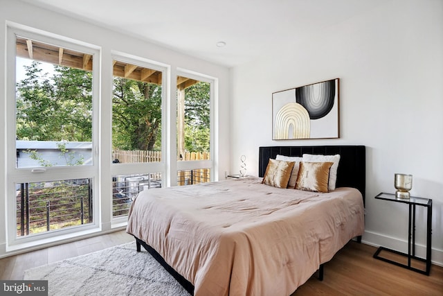 bedroom with access to exterior and hardwood / wood-style flooring