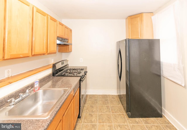 kitchen featuring black fridge, stainless steel gas stove, and sink