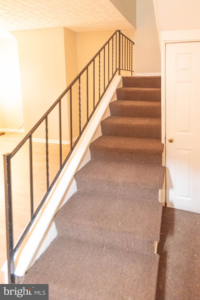 stairs featuring a textured ceiling