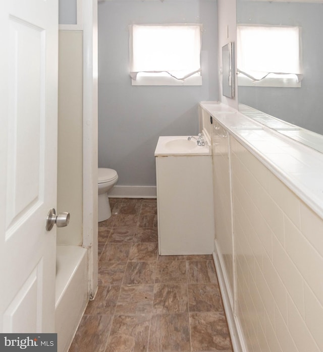 bathroom featuring vanity, a bath, and toilet