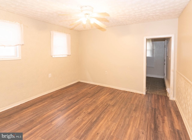 spare room featuring a textured ceiling, ceiling fan, and dark wood-type flooring