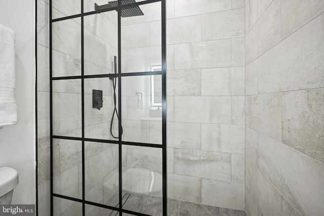 bathroom featuring a tile shower and toilet