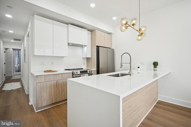 kitchen with kitchen peninsula, appliances with stainless steel finishes, sink, decorative light fixtures, and white cabinetry