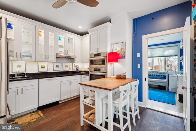 kitchen with dark hardwood / wood-style floors, wooden counters, white cabinetry, double oven, and sink