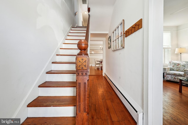 stairway featuring wood-type flooring and a baseboard heating unit