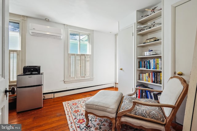 sitting room with dark hardwood / wood-style flooring, an AC wall unit, baseboard heating, and plenty of natural light