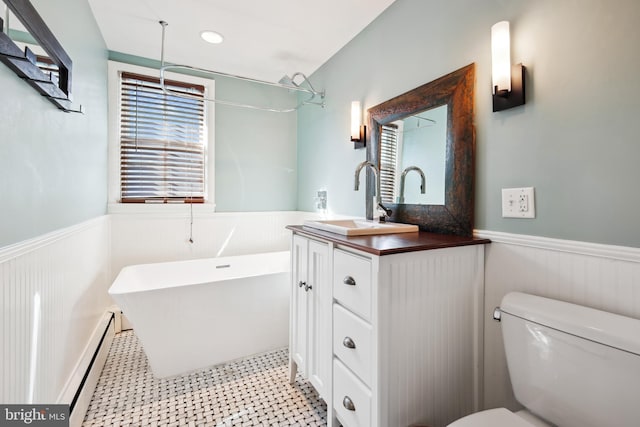 bathroom with a washtub, toilet, vanity, and a baseboard heating unit