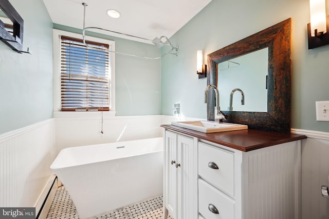 bathroom with a bathing tub, a baseboard heating unit, and vanity