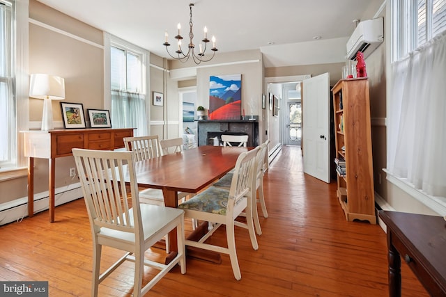 dining space featuring a notable chandelier, a baseboard heating unit, light wood-type flooring, and an AC wall unit