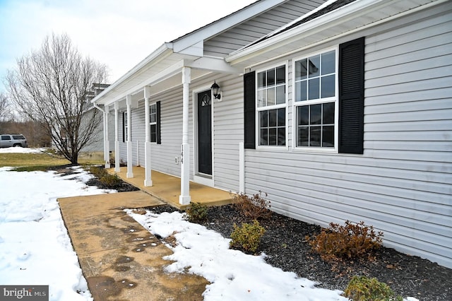 snow covered property entrance featuring a porch