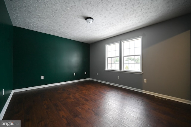 unfurnished room with a textured ceiling and dark hardwood / wood-style floors