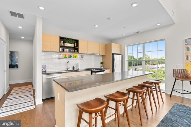 kitchen with hardwood / wood-style floors, a center island, stainless steel appliances, and a breakfast bar area