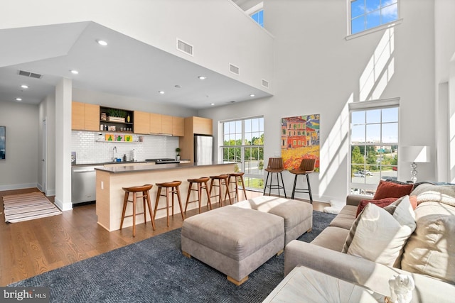 living room with a healthy amount of sunlight, dark hardwood / wood-style flooring, a towering ceiling, and sink