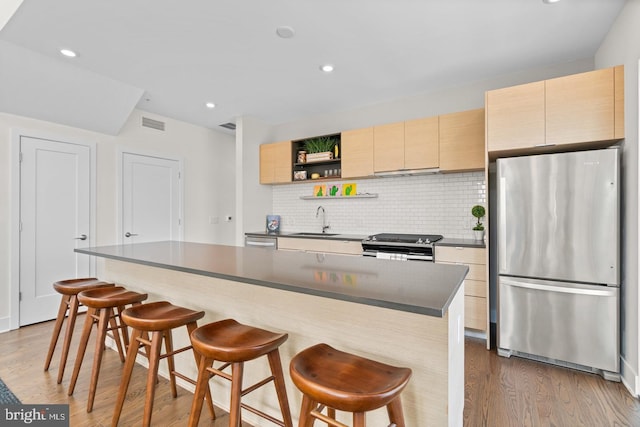 kitchen featuring a kitchen island, sink, stainless steel appliances, and a breakfast bar area