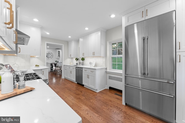 kitchen with backsplash, radiator, white cabinets, and stainless steel appliances