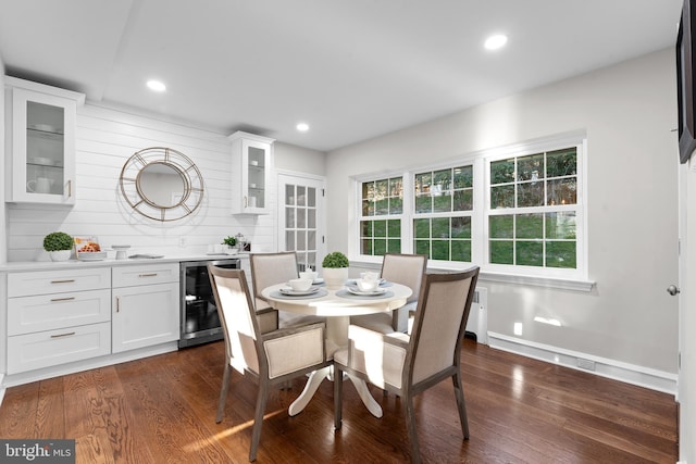 dining area featuring beverage cooler and dark wood-type flooring