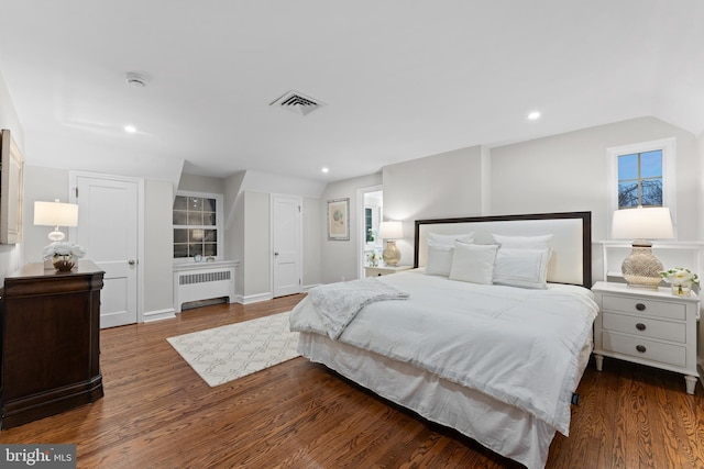 bedroom featuring dark hardwood / wood-style flooring, radiator heating unit, and vaulted ceiling