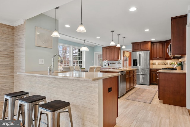 kitchen with appliances with stainless steel finishes, a kitchen breakfast bar, light stone counters, and pendant lighting