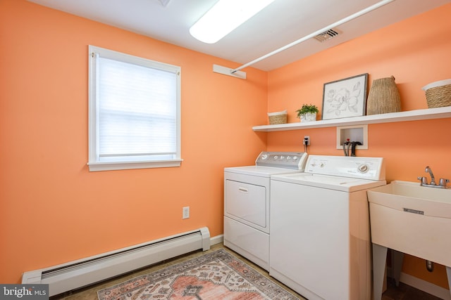 clothes washing area with washer and dryer, baseboard heating, and sink