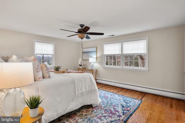 bedroom with ceiling fan, a baseboard radiator, and hardwood / wood-style floors