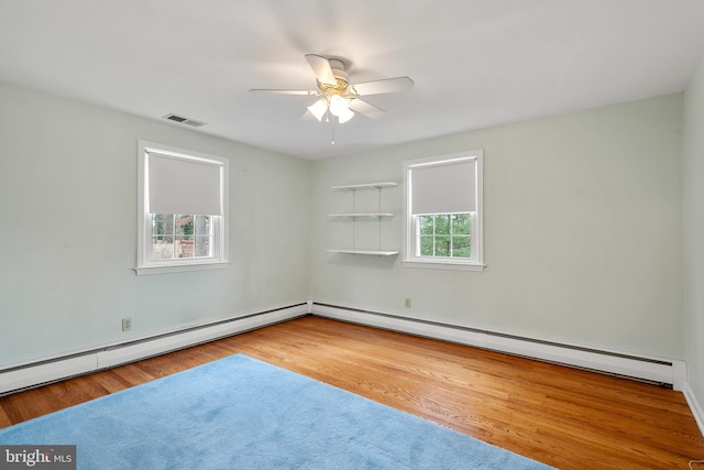 spare room featuring a baseboard heating unit, ceiling fan, and hardwood / wood-style floors