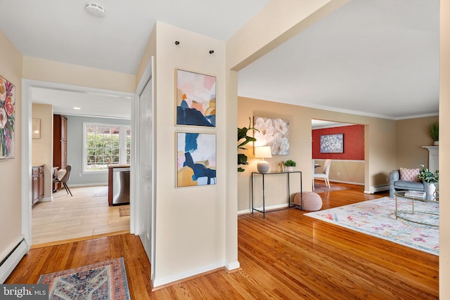 hall with ornamental molding, light hardwood / wood-style flooring, and a baseboard radiator