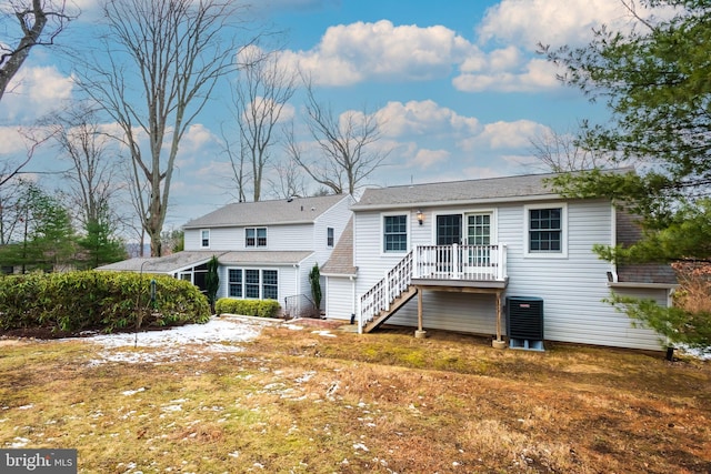 rear view of house featuring central AC unit and a lawn