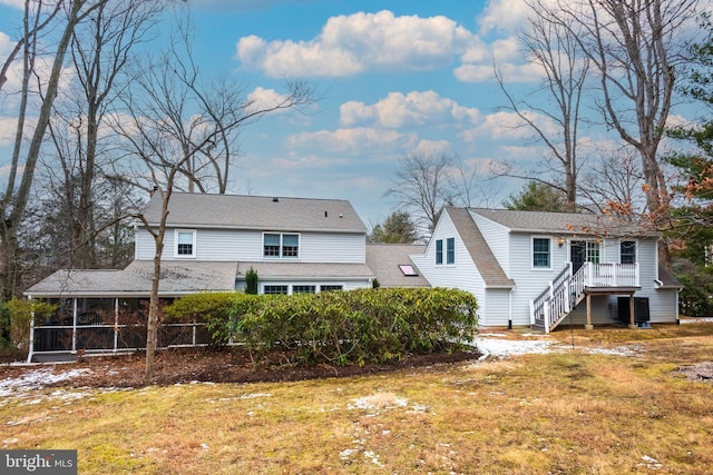 back of house featuring a sunroom and a lawn