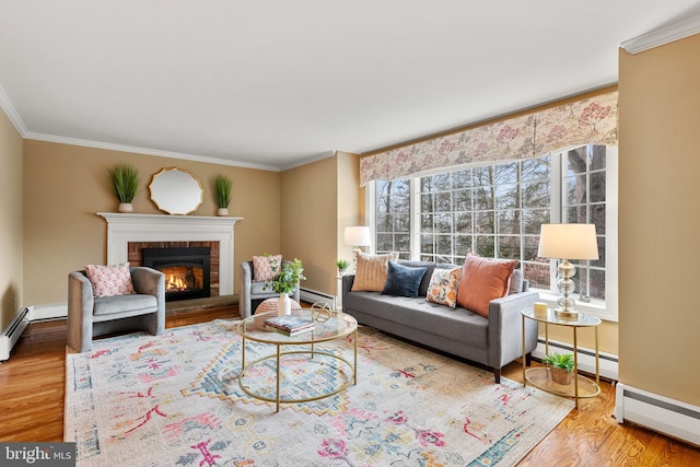 living room with a baseboard heating unit, a brick fireplace, hardwood / wood-style flooring, and ornamental molding