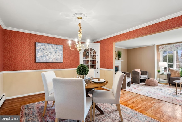 dining space featuring hardwood / wood-style flooring, a baseboard radiator, a notable chandelier, and crown molding