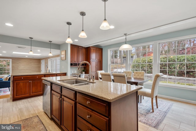 kitchen featuring light stone counters, dishwasher, hanging light fixtures, a center island with sink, and sink