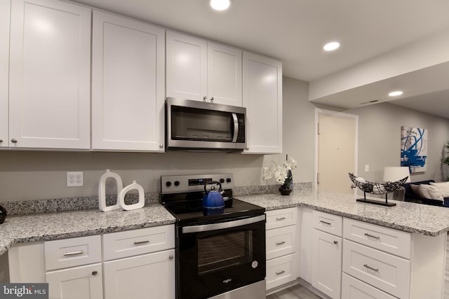 kitchen with kitchen peninsula, stainless steel appliances, and white cabinets