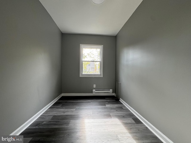 empty room featuring dark hardwood / wood-style floors and a baseboard radiator