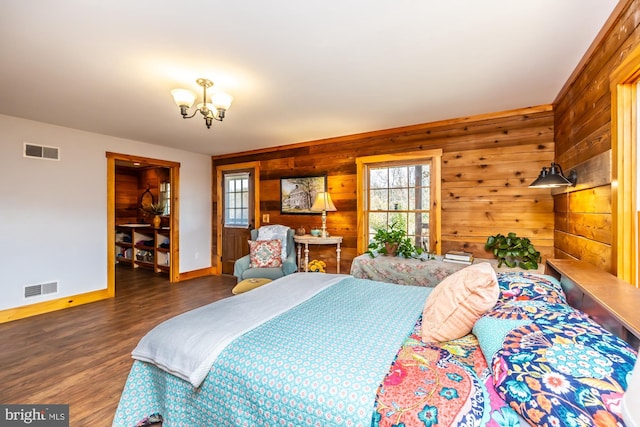 bedroom with dark hardwood / wood-style flooring, an inviting chandelier, and wood walls