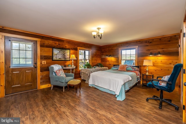 bedroom featuring hardwood / wood-style floors, wooden walls, and a chandelier