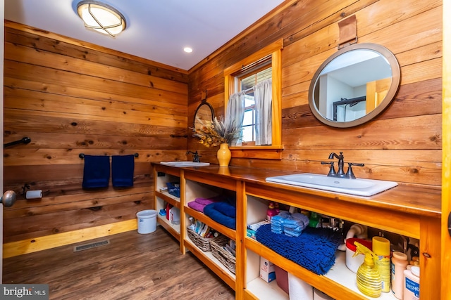 bathroom featuring wood-type flooring, vanity, and wooden walls