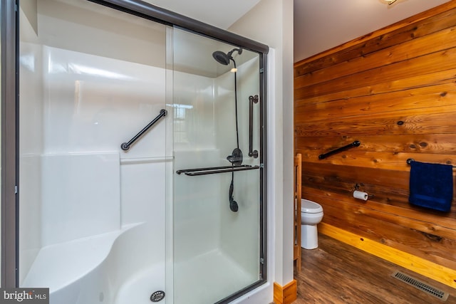 bathroom with wooden walls, toilet, hardwood / wood-style flooring, and walk in shower