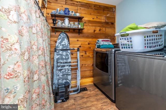 laundry room featuring wood walls, hardwood / wood-style floors, and independent washer and dryer