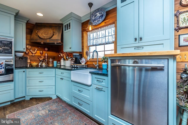 kitchen featuring sink, dark wood-type flooring, hanging light fixtures, premium range hood, and appliances with stainless steel finishes